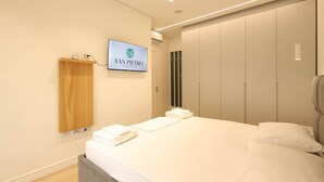 Una habitación de hotel moderna con cama, televisor en la pared y armario.