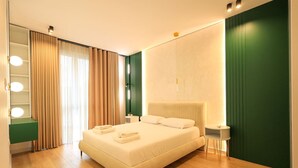 Un dormitorio moderno con una cama grande, mesitas de noche, un espejo y una pared de acento verde.