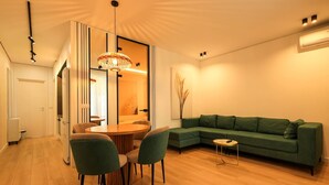 Una sala de estar moderna con un sofá verde, una mesa de comedor de madera con sillas y una lámpara colgante original.