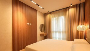 A modern bedroom with a large bed, wooden panel walls, a round mirror, and a hanging light fixture. - SanPietro Vacation Apartment 026 (Plazhi San Pietro)