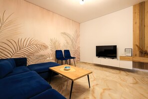 A modern living room with a sectional sofa, a coffee table, and a TV on a wooden cabinet. - SanPietro Vacation Apartment 032 (Plazhi San Pietro)