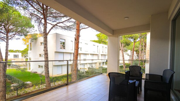 A balcony with a view of a residential area, featuring a seating area with wicker chairs and a tiled floor. - SanPietro Vacation Apartment 032 (Plazhi San Pietro)