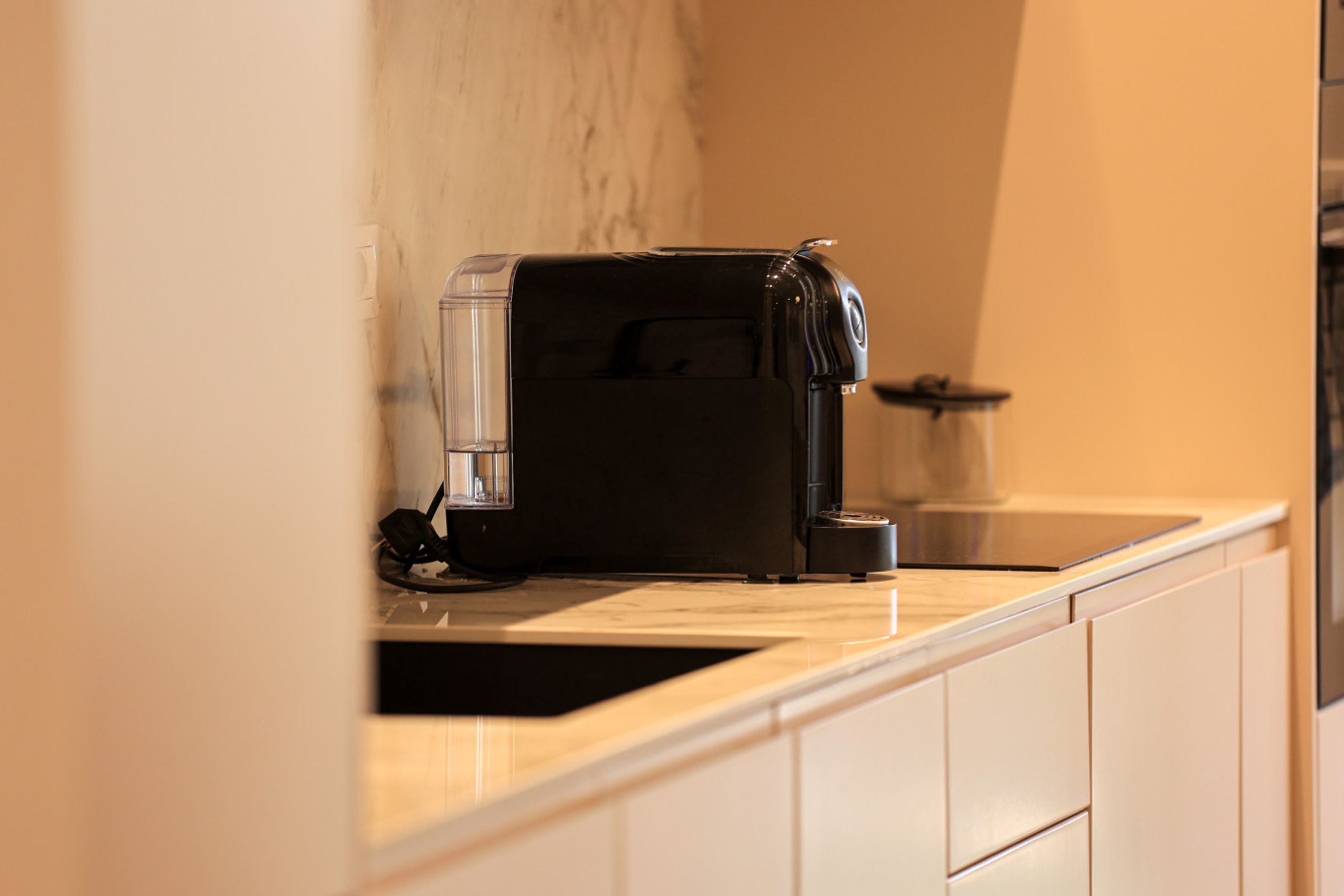 Una cocina con cafetera en la encimera, un fregadero y un armario.
