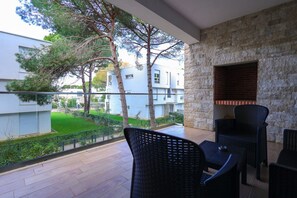 Ein Balkon mit Blick auf ein Wohngebiet, der eine Steinmauer, eine Sitzgelegenheit mit Stühlen und einen kleinen Tisch zeigt.