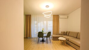 Ein modernes Wohnzimmer mit einer Couch, einem Esstisch mit Stühlen und einer Pendelleuchte.