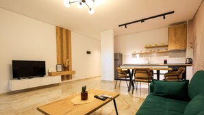 A modern living room with a green sofa, a wooden coffee table, and a flat-screen TV on a white cabinet. - SanPietro Vacation Apartment 035 (Durrës)