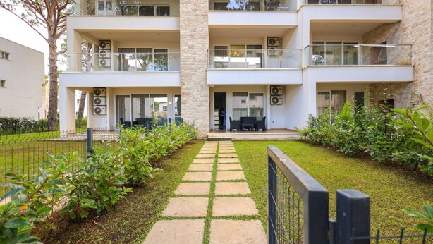 A multi-story building with balconies, a paved pathway, and greenery. - SanPietro Vacation Apartment 035 (Durrës)