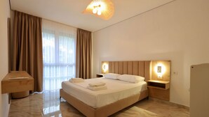 A modern hotel room with a large bed, bedside tables, and a ceiling light fixture. - SanPietro Vacation Apartment 035 (Durrës)