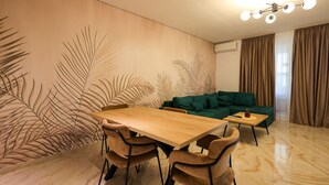 A modern living room with a wooden dining table, two chairs, a green sofa, and a coffee table. - SanPietro Vacation Apartment 035 (Durrës)