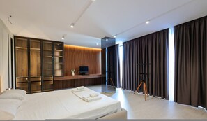 A modern hotel room with a large bed, a wooden wardrobe, a desk with a computer, and a large window with curtains. - SanPietro Elite Villa (Plazhi San Pietro)