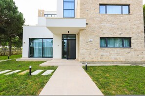 A modern two-story building with a flat roof, large glass windows, and a stone facade. - SanPietro Elite Villa (Plazhi San Pietro)
