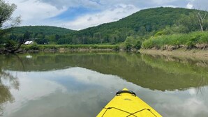A calm river with a yellow kayak in the foreground, surrounded by lush green hills and a partly cloudy sky. - Musician’s Glamping Cabin Near Allegany State Park & Ellicottville (Hinsdale)