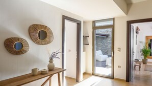 Ein modernes Interieur mit einem Holztischchen, zwei Wandspiegeln und Blick auf einen Sitzbereich im Freien.