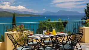 A table set with breakfast items, overlooking a scenic lake with mountains in the background. - Buena Vista Villa - Amazing sea view (Ligia)