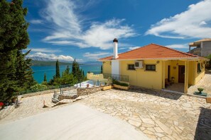 A yellow house with a red-tiled roof, stone flooring, and a view of a lake and mountains. - Buena Vista Villa - Amazing sea view (Ligia)