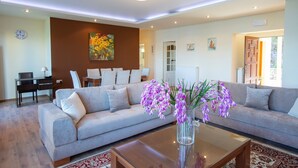 A modern living room with a sofa, coffee table, and a vase of flowers. - Buena Vista Villa - Amazing sea view (Ligia)