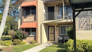 A two-story residential building with a balcony, a covered porch, and a well-maintained lawn. - Well kept condo in Fort Myers on an executive golf course and view of first hole (Fort Myers)