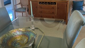 A living room with a glass coffee table, a wooden cabinet, a mirror, and two wicker chairs. - Well kept condo in Fort Myers on an executive golf course and view of first hole (Fort Myers)