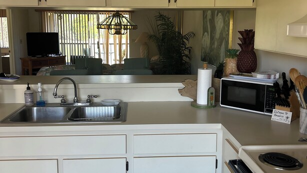 A kitchen with white cabinets, a sink, a microwave, and a stove. - Well kept condo in Fort Myers on an executive golf course and view of first hole (Fort Myers)
