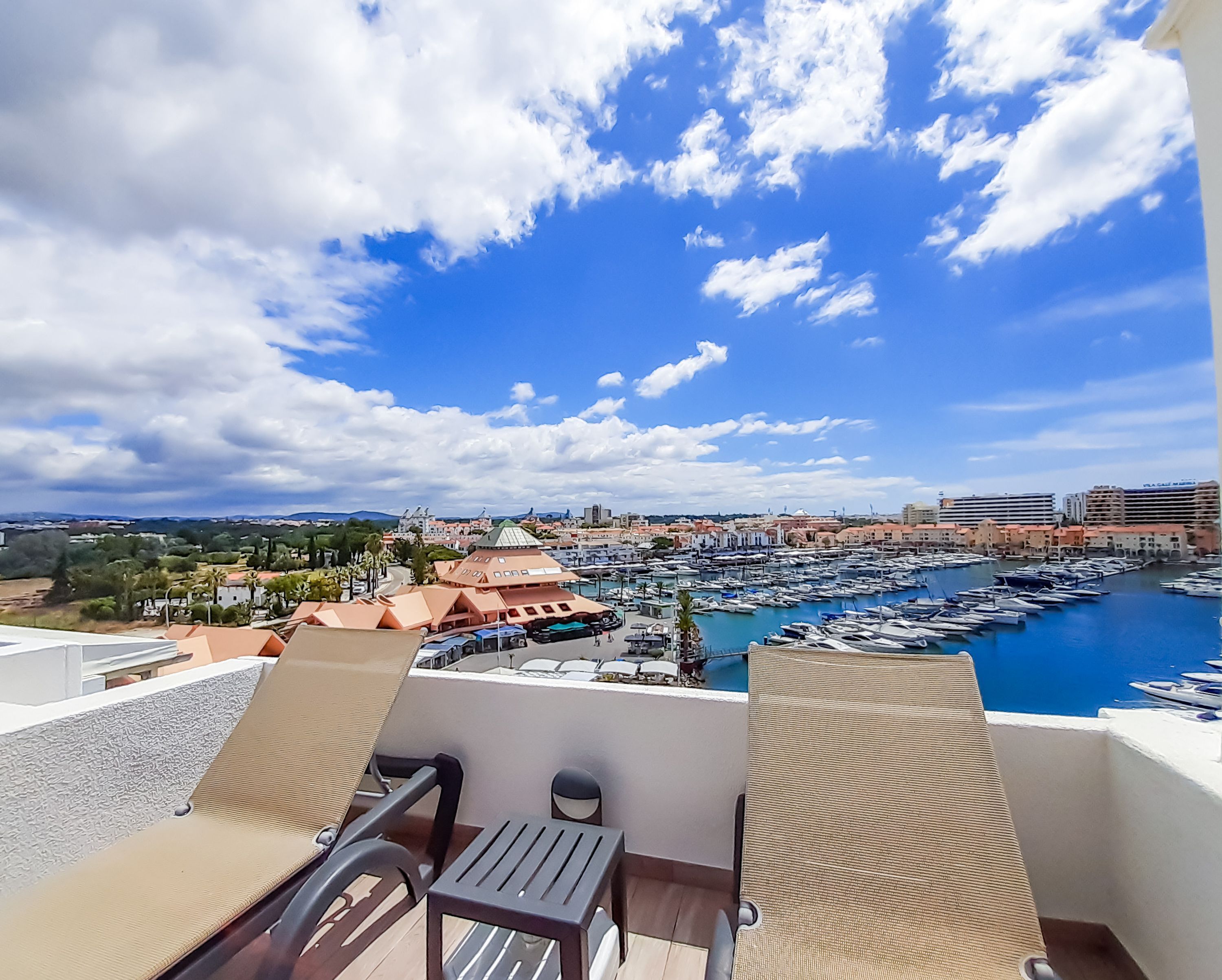 A balcony with a view of a marina, boats, and a cityscape.