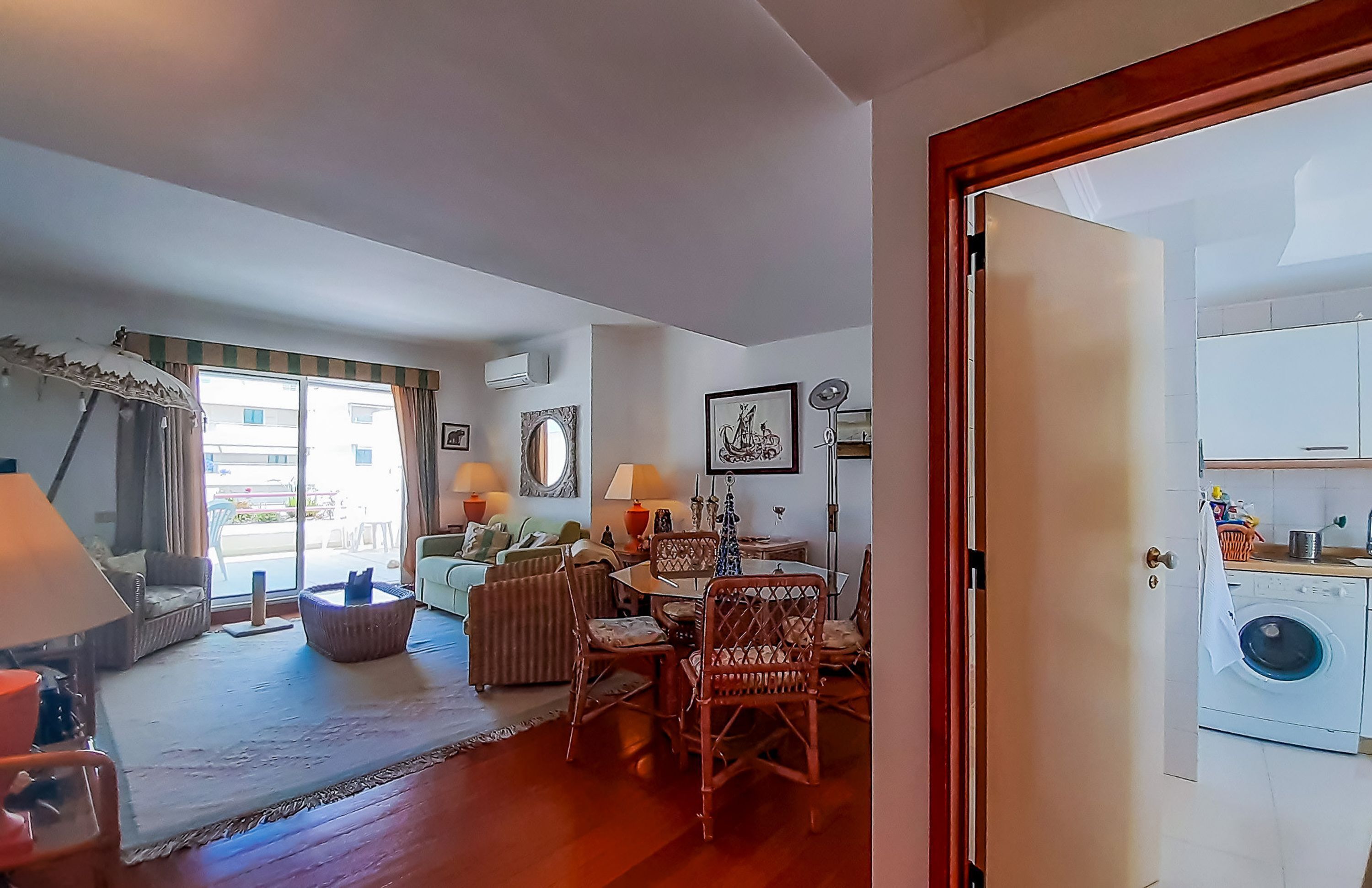 A living room with a dining area, a sofa, a coffee table, and a door leading to a laundry room.