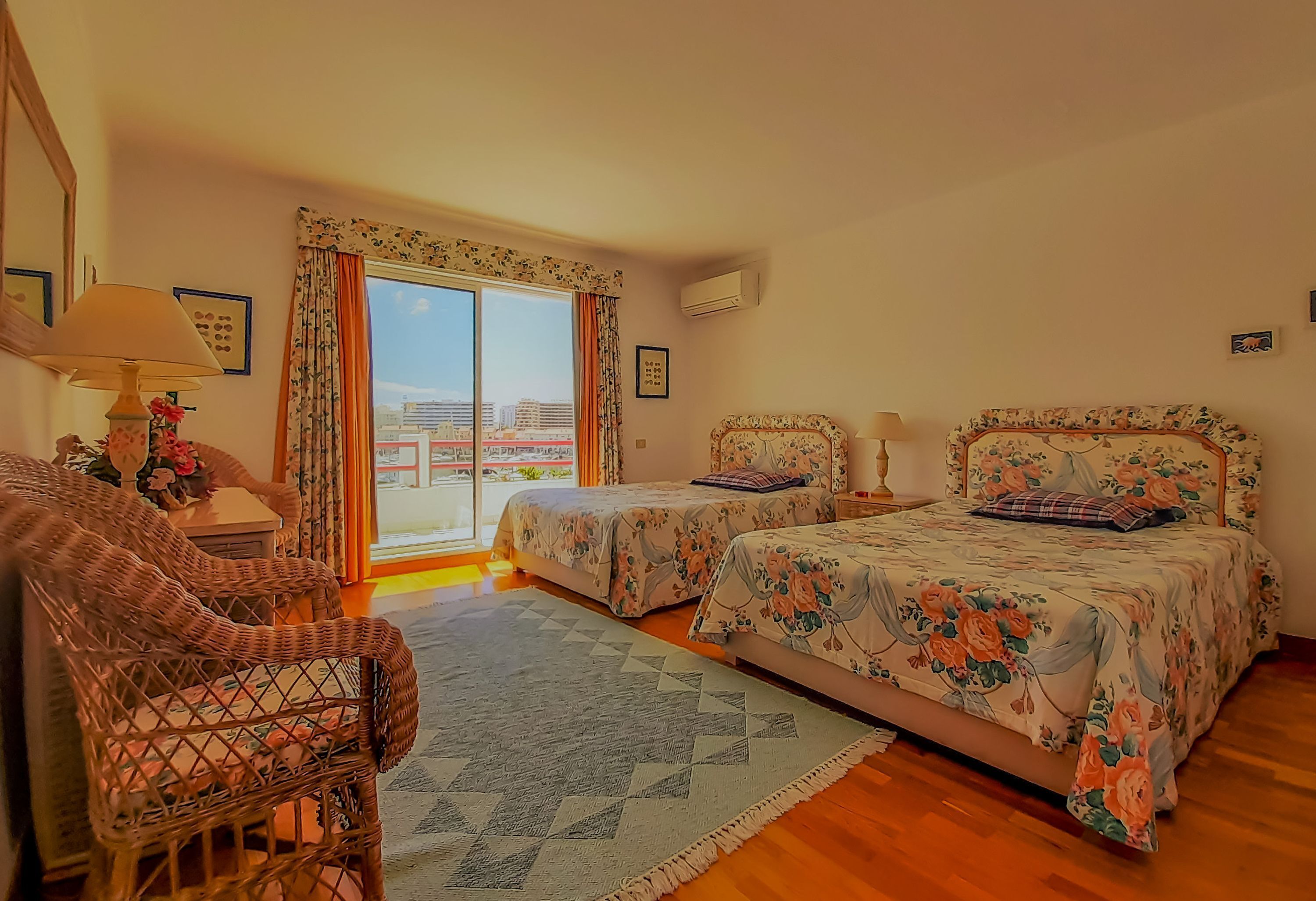 A bedroom with two beds, a sofa, and a window with curtains.