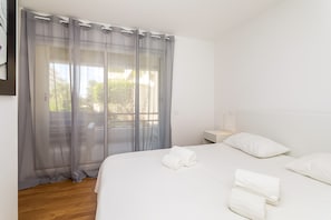 Ein Hotelzimmer mit einem Bett, weißen Kissen, einem Nachttisch und transparenten Vorhängen.