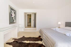 Ein Schlafzimmer mit einem Bett, einem Schreibtisch, einem Stuhl, einem Cowhide-Teppich, einer Lampe und einem Bild an der Wand.