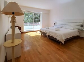 Un dormitorio con cama, mesitas de noche, una lámpara y vistas a través de un ventanal corredero.