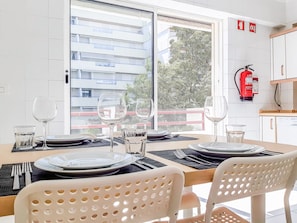 Comedor con una mesa dispuesta para cuatro, con platos, vasos y cubiertos.