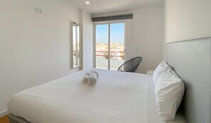 Een hotelkamer met een bed, een stoel en uitzicht op gebouwen door een raam.