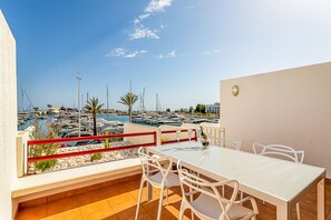 A terrace with a table and chairs overlooking a marina with boats. - Onde a Marina é Casa | T2 HsRentals Vilamarina (Vilamoura)
