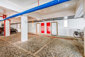 A parking garage with numbered parking spaces, a bicycle, and a red and white door. - Onde a Marina é Casa | T2 HsRentals Vilamarina (Vilamoura)