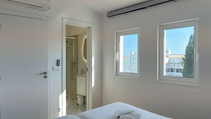 A bedroom with a bed, a shower, and two windows with a view of buildings. - Vila Shradhala | V4 HsR Marina Vilamoura (Vilamoura)
