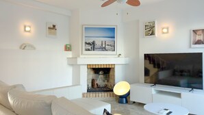 A modern living room with a fireplace, a large flat-screen TV, a sofa, and a coffee table. - Vila Shradhala | V4 HsR Marina Vilamoura (Vilamoura)