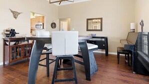 A modern kitchen with a dining area, wooden flooring, and a chandelier.