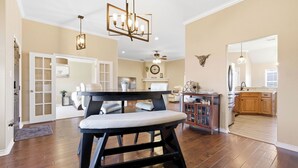 A spacious living room with a dark wooden bench, a chandelier, and a fireplace.