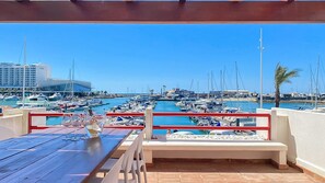 A marina with boats, a building in the background, and a table with chairs. - Que sonho! Vista Marina | T2 HsRentals Vilamarina (Vilamoura)