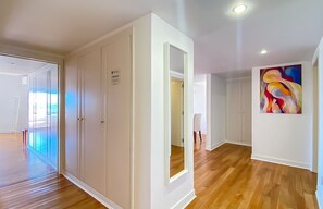 Une pièce spacieuse avec un plancher en bois, une grande armoire, une plaque signalétique personnalisée sur la porte et une peinture abstraite aux couleurs vives accrochée au mur.