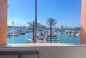 A marina with boats docked, palm trees, and a clear sky. - Daytona Marina Vilamoura | T1 HsR Vilamoura (Vilamoura)