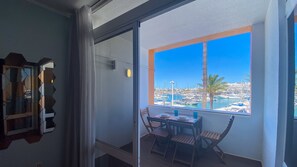A balcony with a view of a marina, a table with chairs, and a glass door. - Daytona Marina Vilamoura | T1 HsR Vilamoura (Vilamoura)