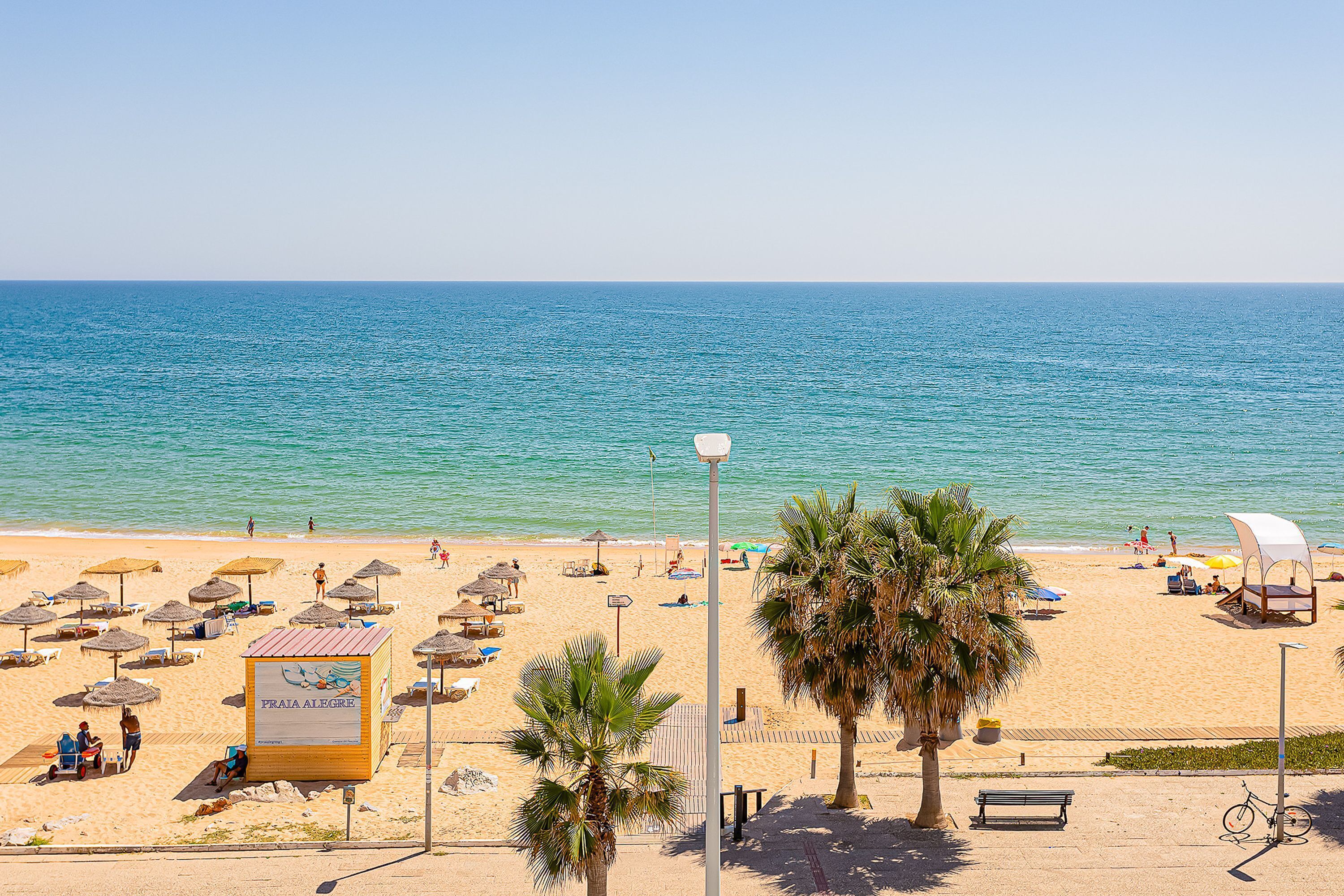 A beach with umbrellas, lounge chairs, and a signboard.