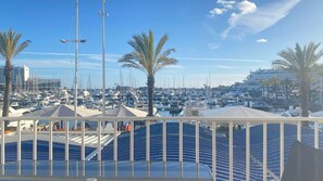 Un port esportiu amb vaixells amarrats, palmeres i un cel serè.