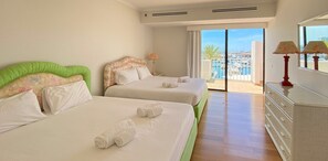 A hotel room with two beds, a balcony with a view of the marina, and a dresser with lamps. - Intemporal Duplex Marina | T2 HsRentals Vilamoura (Vilamoura)