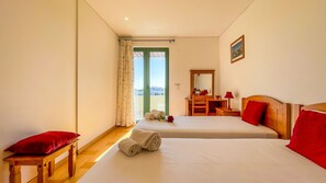 A hotel room with two beds, a desk, a chair, a mirror, and a view through a green door. - Aquamar Sunset | T2 HsRentals Marina Vilamoura (Vilamoura)