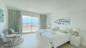 Habitación de hotel con un amplio ventanal corredizo, dos camas, un escritorio y una silla.