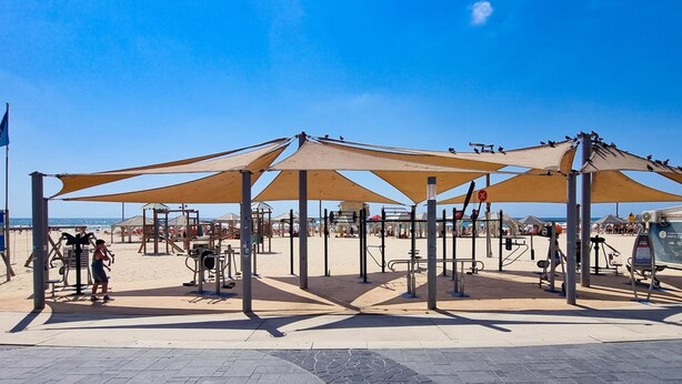 A beachside fitness area with exercise equipment and shaded areas. - Geula Tulipe in Tel Aviv-Yafo (Tel Aviv-Yafo)