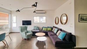 A modern living room with a sofa, armchair, coffee table, and a TV. - Geula Tulipe in Tel Aviv-Yafo (Tel Aviv-Yafo)