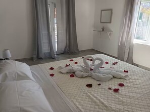 A hotel room with a bed, a bedside table, a mirror, and a window with curtains.
