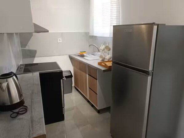 A modern kitchen with a stainless steel refrigerator, a coffee maker, and a trash bin.